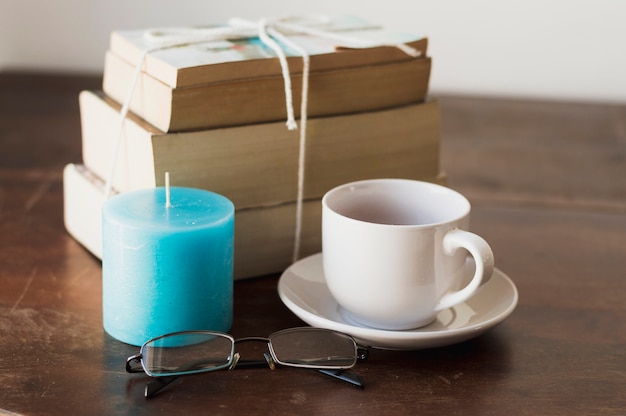 Pile de livres, bougie bleue, café et lunettes