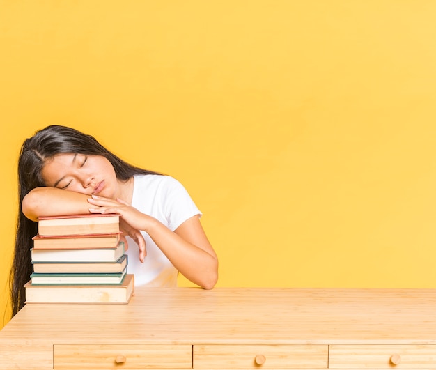 Photo gratuite pile de livres sur le bureau et femme endormie