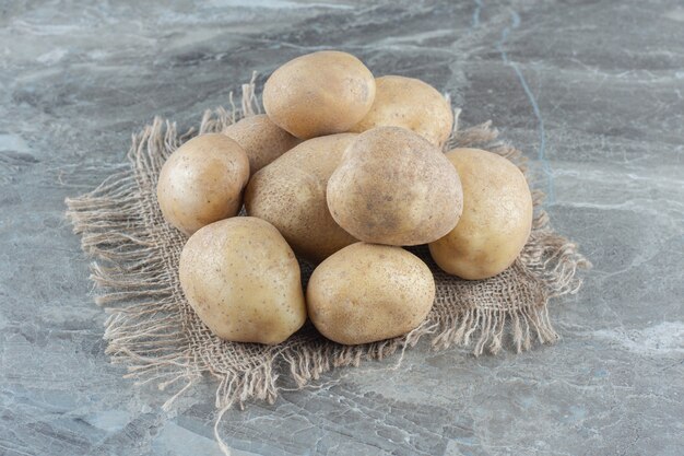 Une pile de pommes de terre sur le dessous de plat sur la table en marbre.