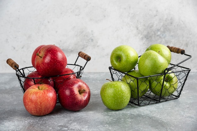 Pile de pommes vertes et rouges fraîches placées dans des paniers métalliques.