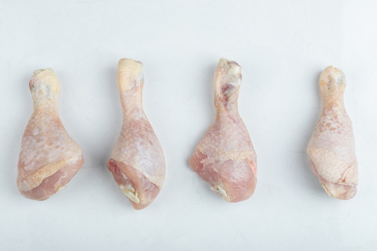 Photo gratuit pilon de poulet cru frais sur fond blanc.