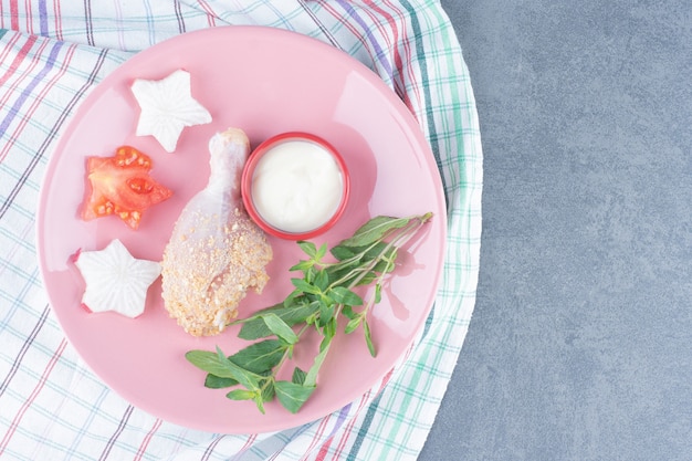 Pilon de poulet cru et mayonnaise sur plaque rose.