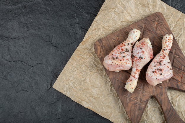 Photo gratuite pilon de poulet cru vue de dessus sur planche de bois.