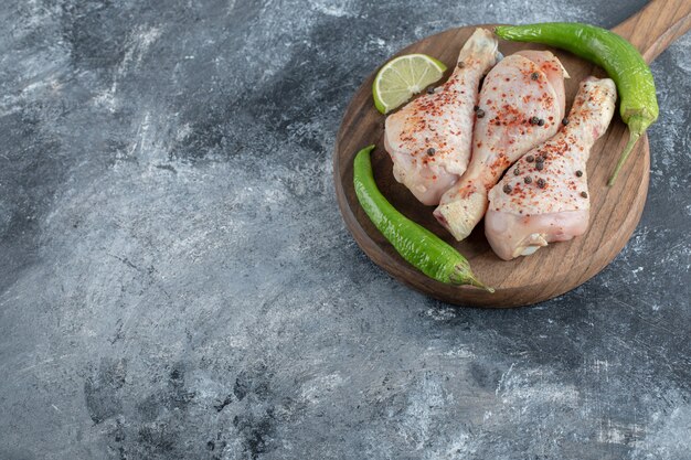 Pilons de poulet cru bio frais sur planche à découper en bois.