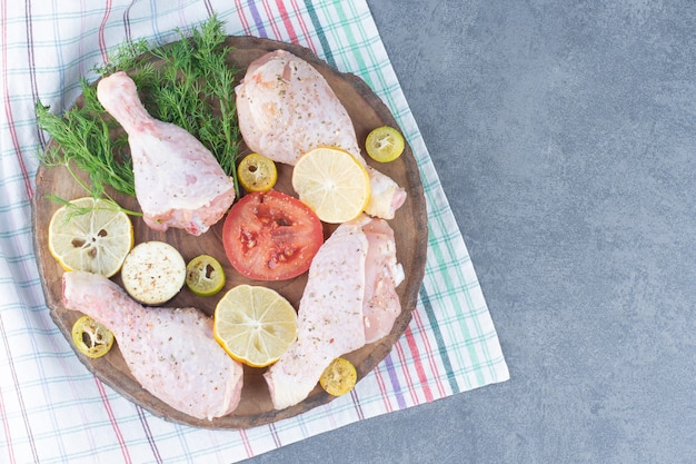 Photo gratuite pilons de poulet cru sur morceau de bois.