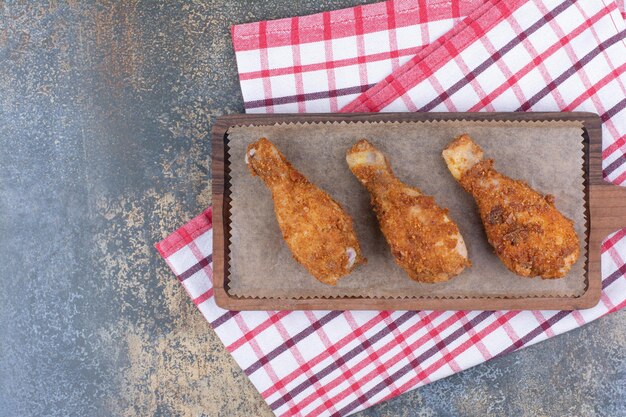 Pilons de poulet grillés sur planche de bois avec nappe. photo de haute qualité