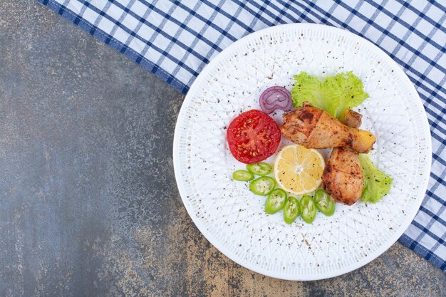 Pilons de poulet grillés sur plaque blanche avec des légumes. photo de haute qualité