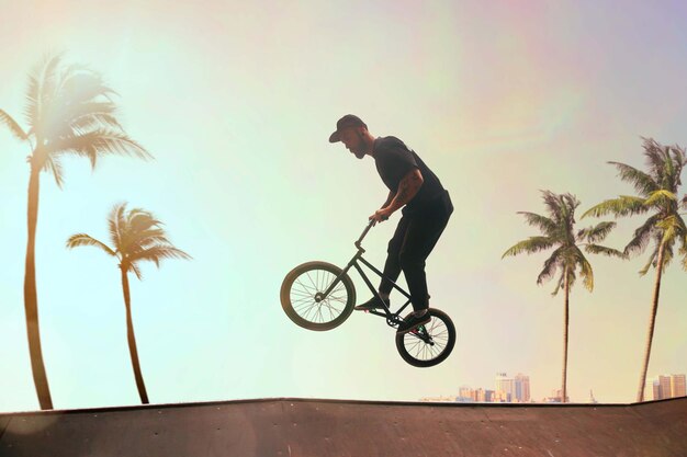 Le pilote de BMX exécute des tours dans le skatepark au coucher du soleil