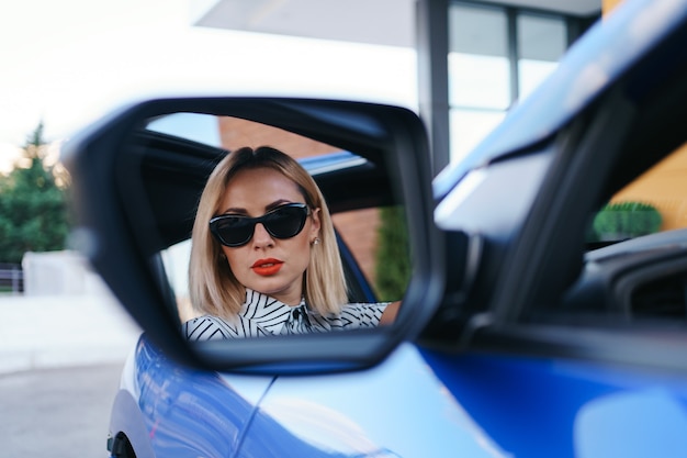 Pilote de jeune femme à la recherche dans le rétroviseur de la voiture, s'assurant que la ligne est libre avant de faire un virage.