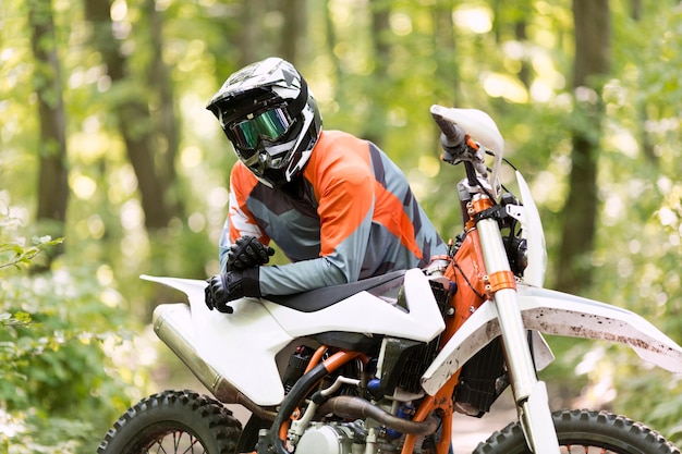 Pilote de moto élégant posant dans la forêt