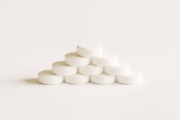 Pilules blanches formant la pyramide sur le fond blanc