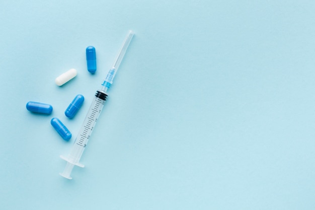 Pilules bleues et blanches avec seringue
