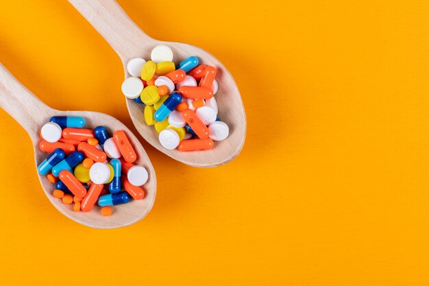 Pilules colorées dans des cuillères en bois