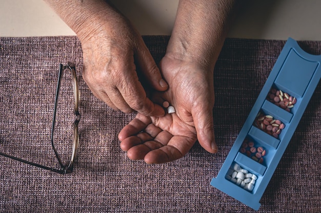 Pilules dans les mains d'une vieille femme vue de dessus