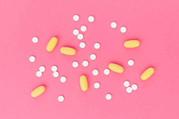 Pilules médicales blanches et jaunes sur fond rose