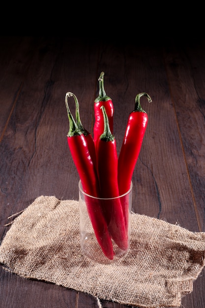 piment rouge en verre sur un sac sur une surface en bois