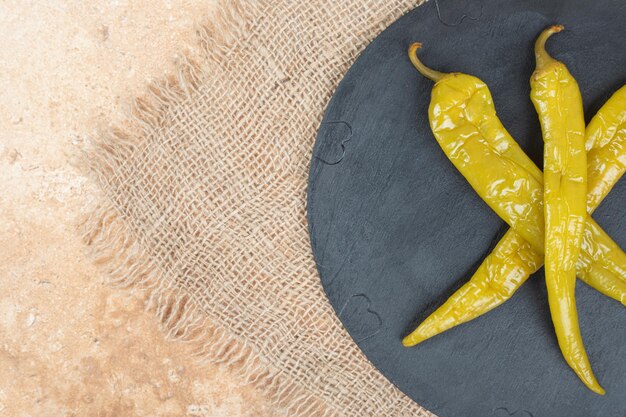 Piments marinés sur plaque noire avec de la toile de jute.