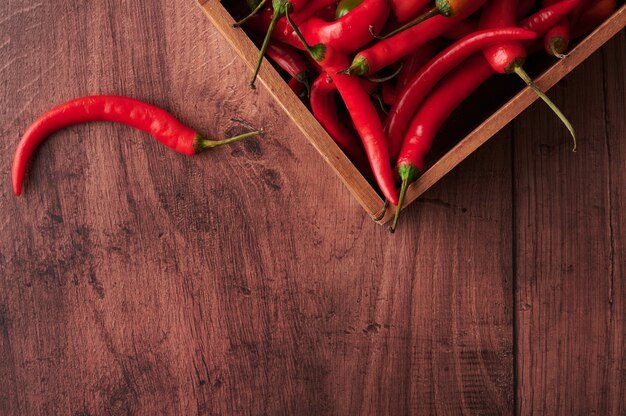 Piments rouges dans une boîte posée sur une surface en bois