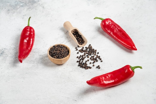 Piments rouges et grains de poivre sur fond de marbre.