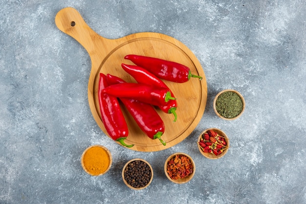 Photo gratuite piments rouges sur planche de bois avec des épices.