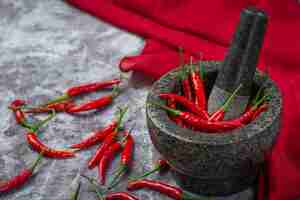 Photo gratuite les piments rouges sont dans un mortier en pierre sur une surface noire.