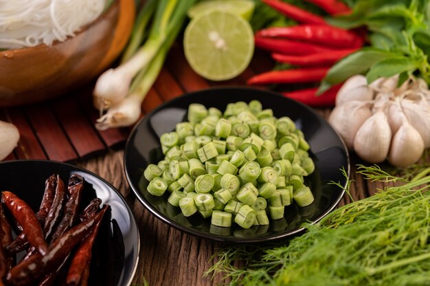 Piments séchés frits dans une assiette noire avec des lentilles. Les concombres et l'ail sont placés sur la table en bois