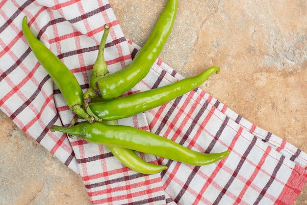 Piments verts sur nappe sur surface en marbre.