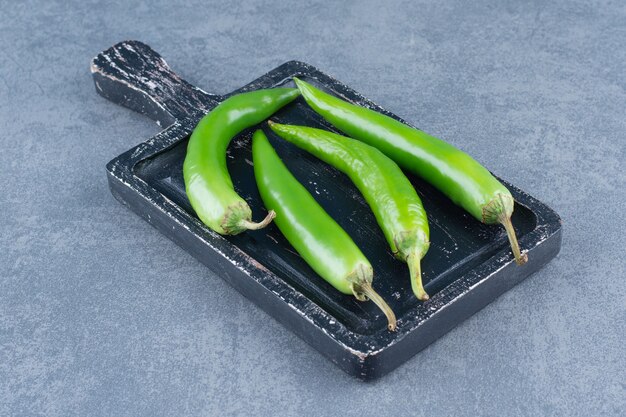 Piments verts sur planche de bois.