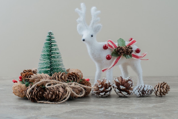 Pin, cônes et cerf jouet sur table en marbre.