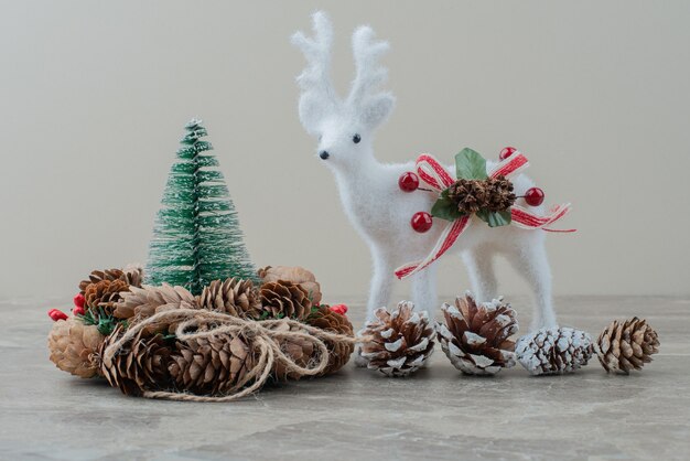 Pin, cônes et cerf jouet sur table en marbre.