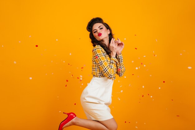 Pin-up romantique dansant sur fond jaune. Photo de Studio de jeune femme ludique en jupe blanche.
