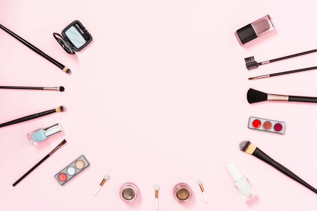 Pinceaux de maquillage et produits cosmétiques décoratifs sur fond rose avec un espace pour écrire le texte