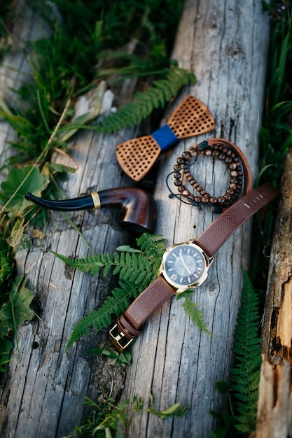 Photo gratuite pipe en bois, noeud papillon et bracelets se trouvent sur les blocs