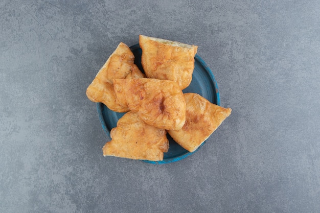 Piroshki tranché avec pommes de terre sur plaque bleue.