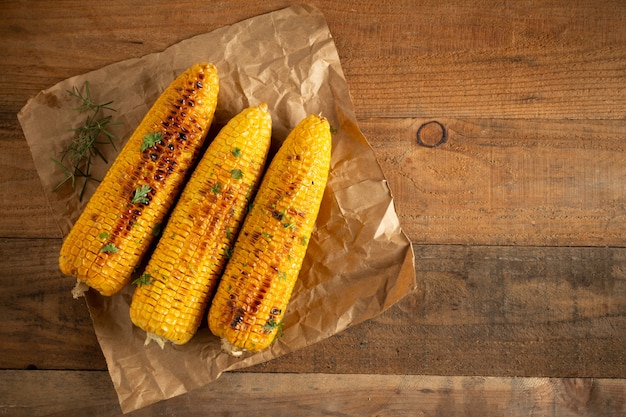 Épis de maïs grillés sur fond de bois.