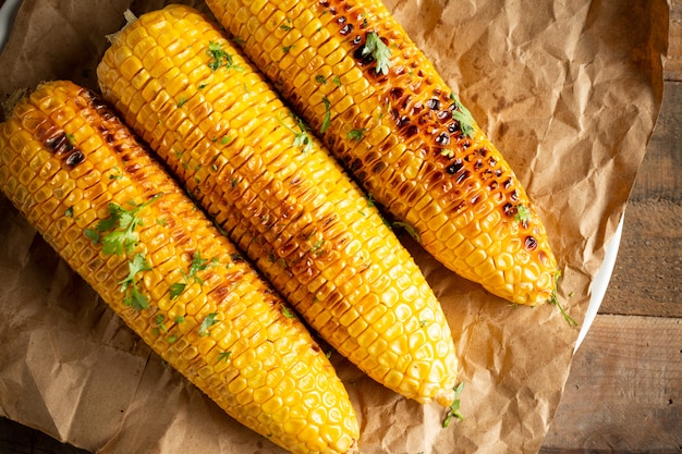 Épis de maïs grillés sur fond de bois.