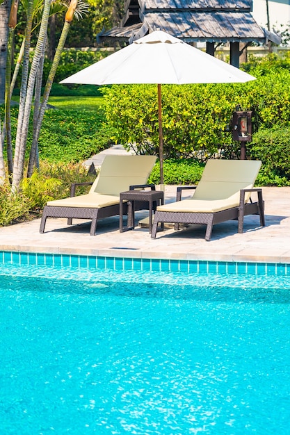 Photo gratuite piscine extérieure avec plage mer océan autour d'un parasol et d'une chaise pour des vacances de voyage de loisirs