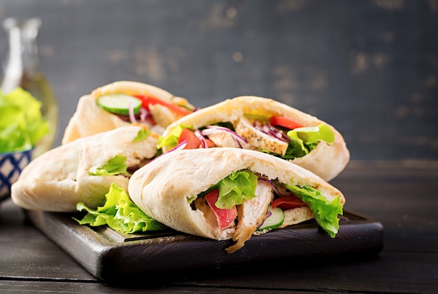 Pita farci au poulet, tomate et laitue sur table en bois. Cuisine du Moyen-Orient.