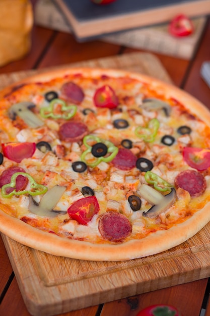 Pizza au pepperoni avec poivrons, tranches de tomates, champignons et olives.