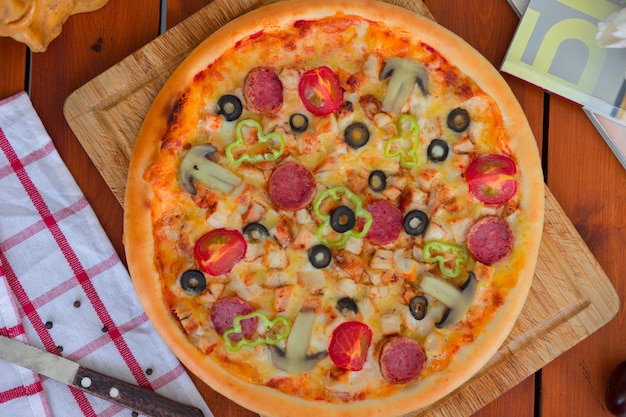 Pizza au pepperoni avec poivrons, tranches de tomates, champignons et olives.
