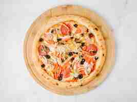 Photo gratuite pizza aux olives pepperoni sur une assiette en bois.