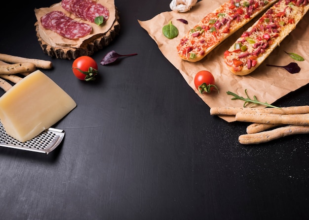 Pizza baguette avec des ingrédients italiens sur une surface de pierre noire