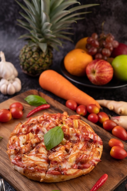 Pizza dans un plateau en bois avec tomates Chili et basilic.