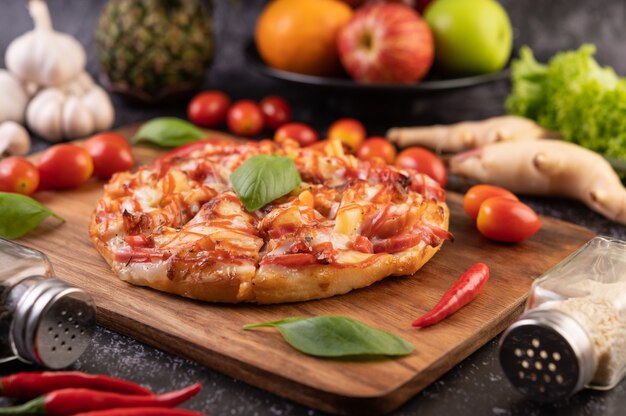 Pizza dans un plateau en bois avec tomates Chili et basilic.