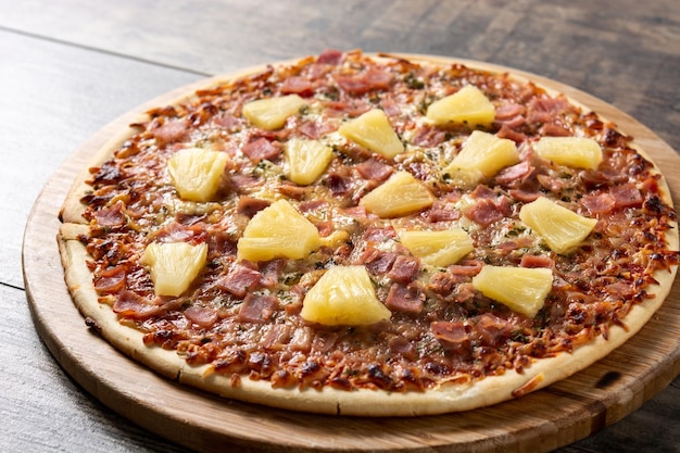 Pizza hawaïenne avec jambon d'ananas et fromage sur table en bois