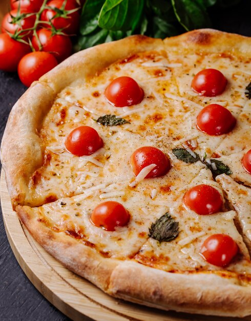 Pizza Margarita avec tomates cerises et feuilles de basilic.