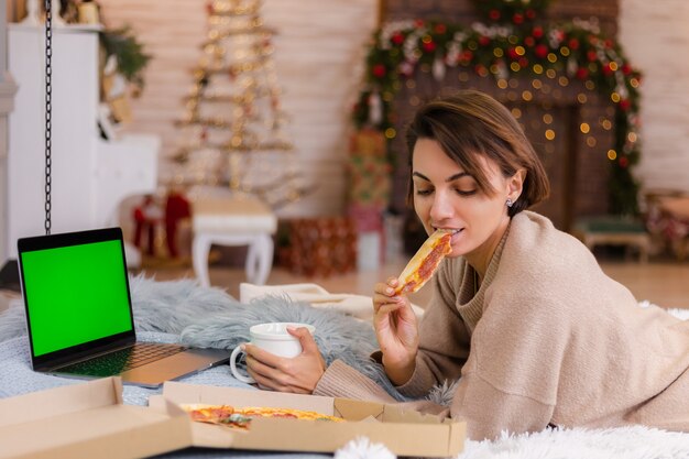 Pizza de restauration rapide femme est de la livraison sur le lit dans la chambre à la maison à Noël Nouvel An.