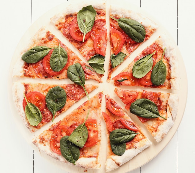 Pizza traditionnelle avec des tranches de tomate et des feuilles de basilic