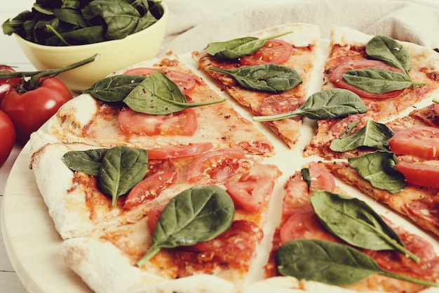 Pizza traditionnelle avec des tranches de tomate et des feuilles de basilic