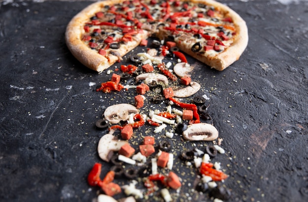 Pizza tranchée et ingrédients sur un tableau en pierre noire